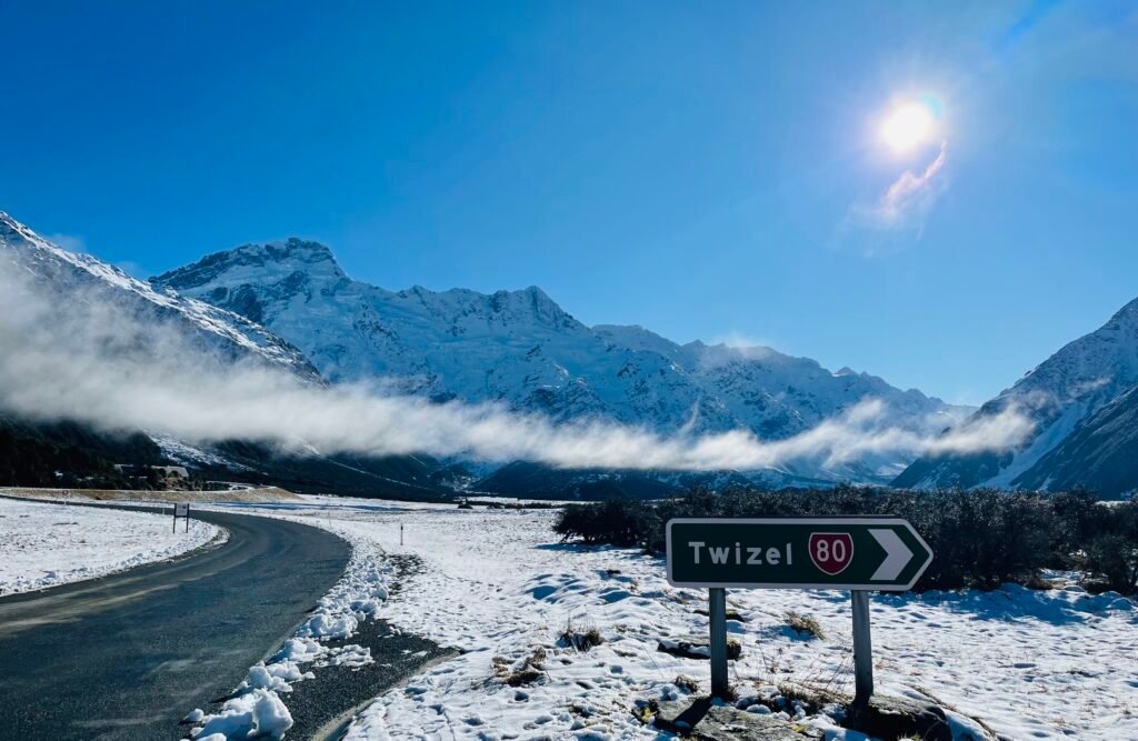 Twizel road sign with snowy mountain backdrop on a clear day.