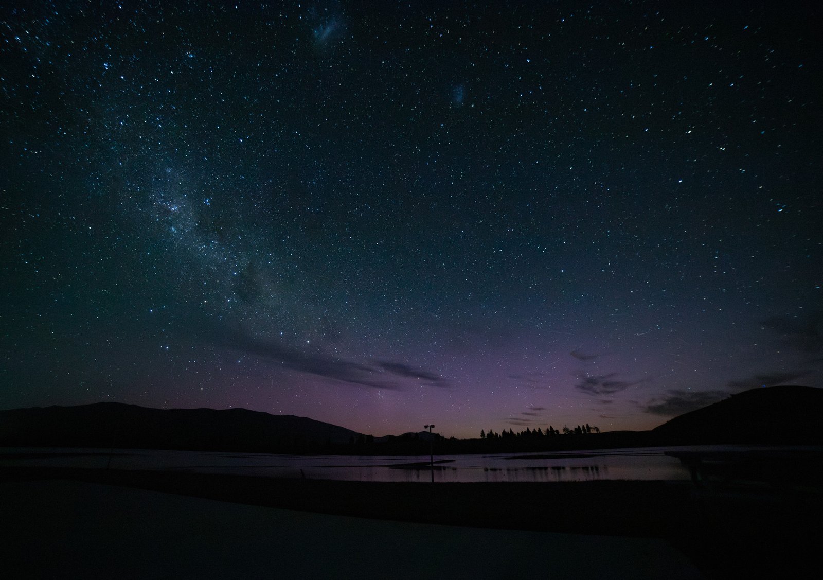 Aurora glowing above Lake Ruataniwha with the Milky Way stretching across the night sky and the Large and Small Magellanic Clouds visible