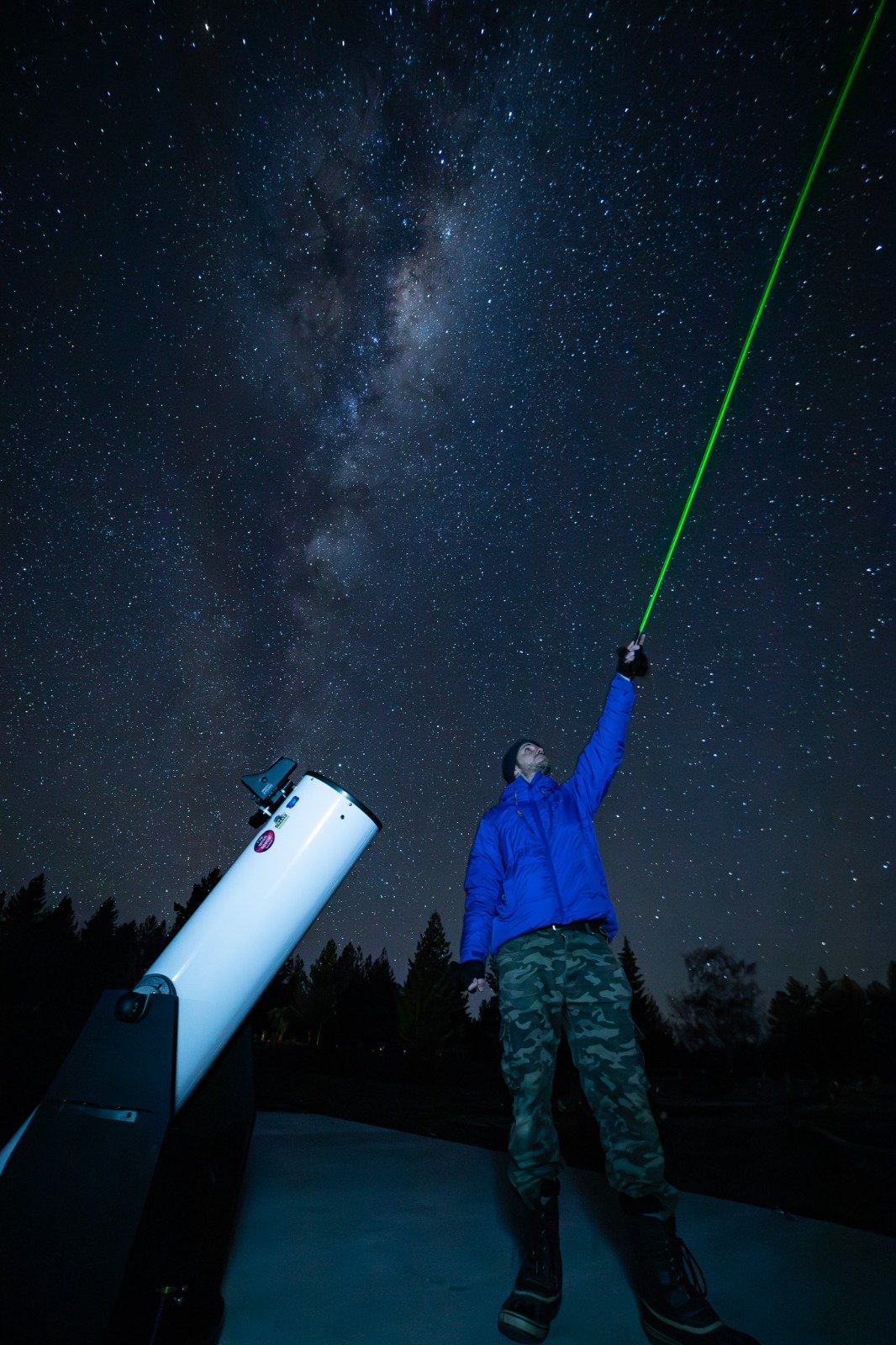Stargaze Mackenzie guide pointing a laser at the night sky while explaining stars and constellations during a stargazing tour